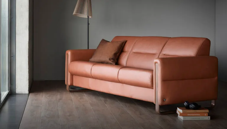 Luxury leather sofa with hardwood finishes for the legs. The leather is a burnt orange colour.